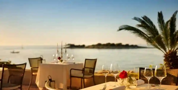 Gedeckter Tisch in einem Restaurant mit direktem Blick auf das Meer bei warmer Abendstimmung