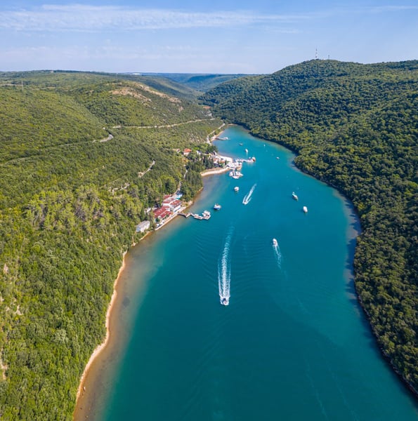 Bootsfahrt auf dem Limfjord durch eine grüne Flusslandschaft aus der Luft gesehen