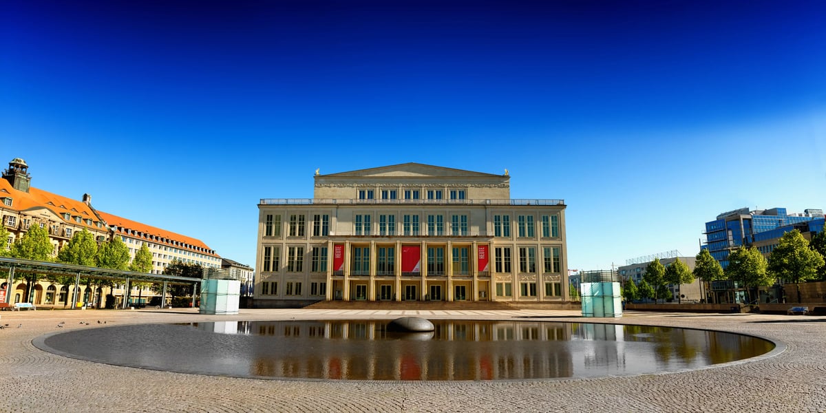 Das Opernhaus in Leipzig an einem weiten Platz unter strahlend blauem Himmel