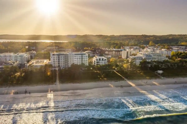 Luftaufnahme eines Hotels direkt an der Strandpromenade von Rügen bei tief stehender Sonne