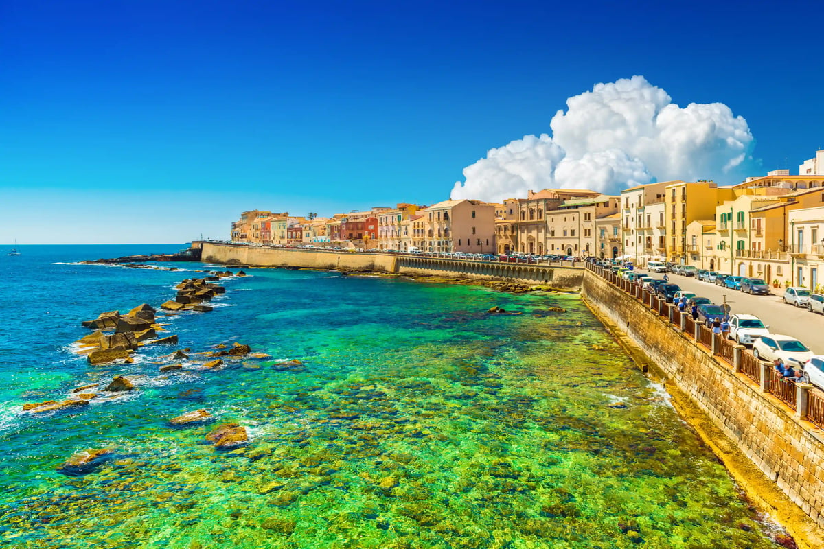 Promenade côtière historique de Siracusa avec maisons colorées et mer turquoise
