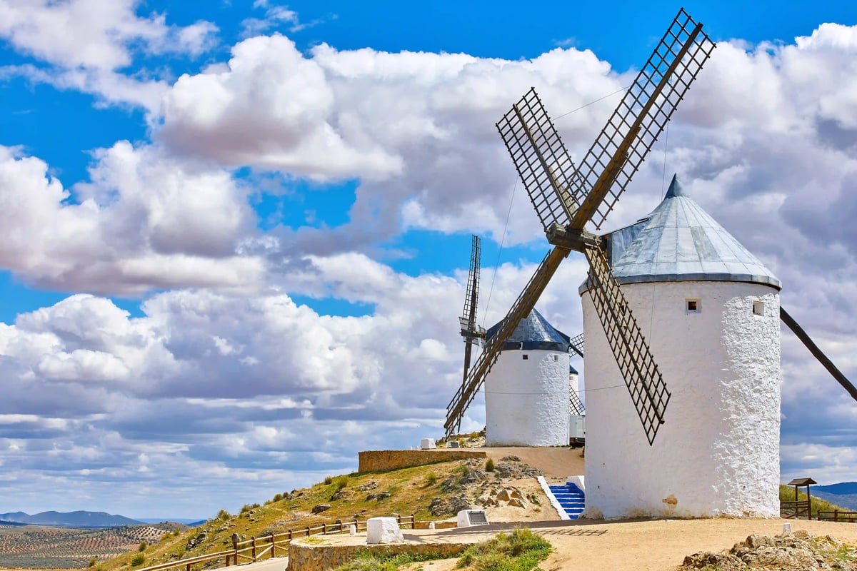 Historische weisse Windmühlen auf einem Hügel in Consuegra unter blauem Himmel mit Wolken