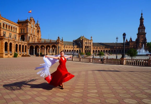 Flamenco Tänzerin in rotem Kleid mit ausgebreiteten Armen auf einem Platz in Spanien