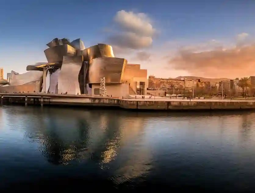 Modernes Guggenheim Museum in Bilbao mit reflektierender Metallfassade am Fluss