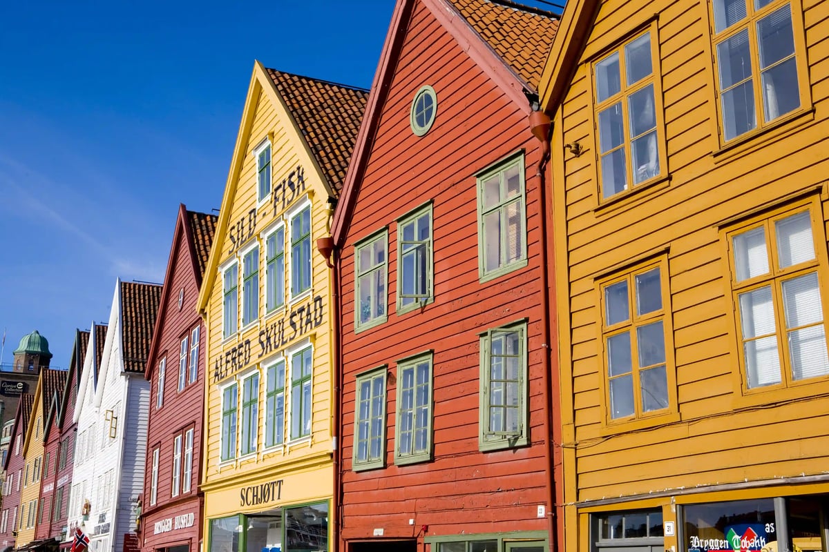 Bunte Holzhäuser in Bergen in Norwegen, dicht aneinander gereiht, mit Fenstern und Giebeln im Sonnenlicht
