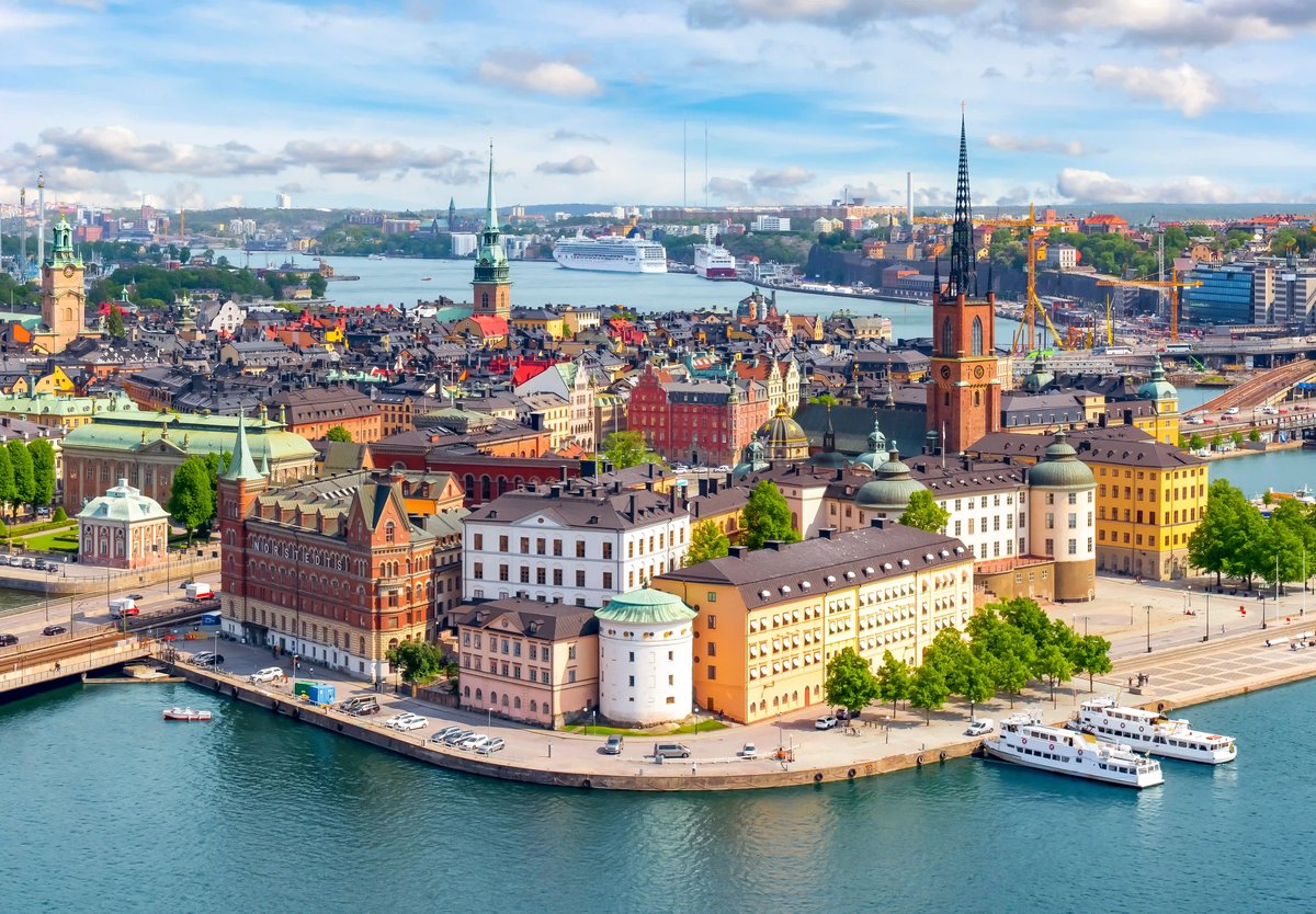 Weitläufige Stadtansicht von Stockholm mit historischen Gebäuden, Kirchtürmen und Wasserwegen an einem sonnigen Tag