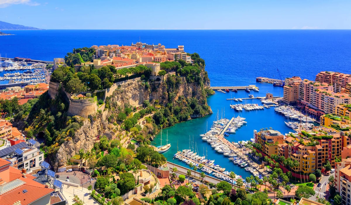 Luftaufnahme von Monaco mit Altstadt auf einem Felsen, Jachthäfen, Hochhäusern und tiefblauem Mittelmeer