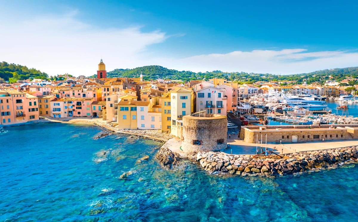 Blick auf den Hafen von Saint-Tropez mit bunten Häusern, Yachten, Festungsturm und klarem blauem Wasser
