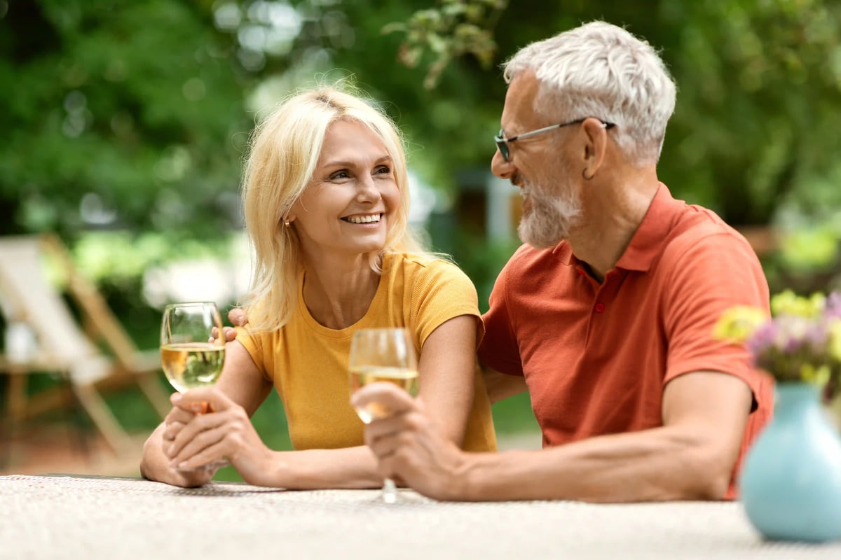 Älteres Paar sitzt im Garten und geniesst gemeinsam ein Glas Weisswein
