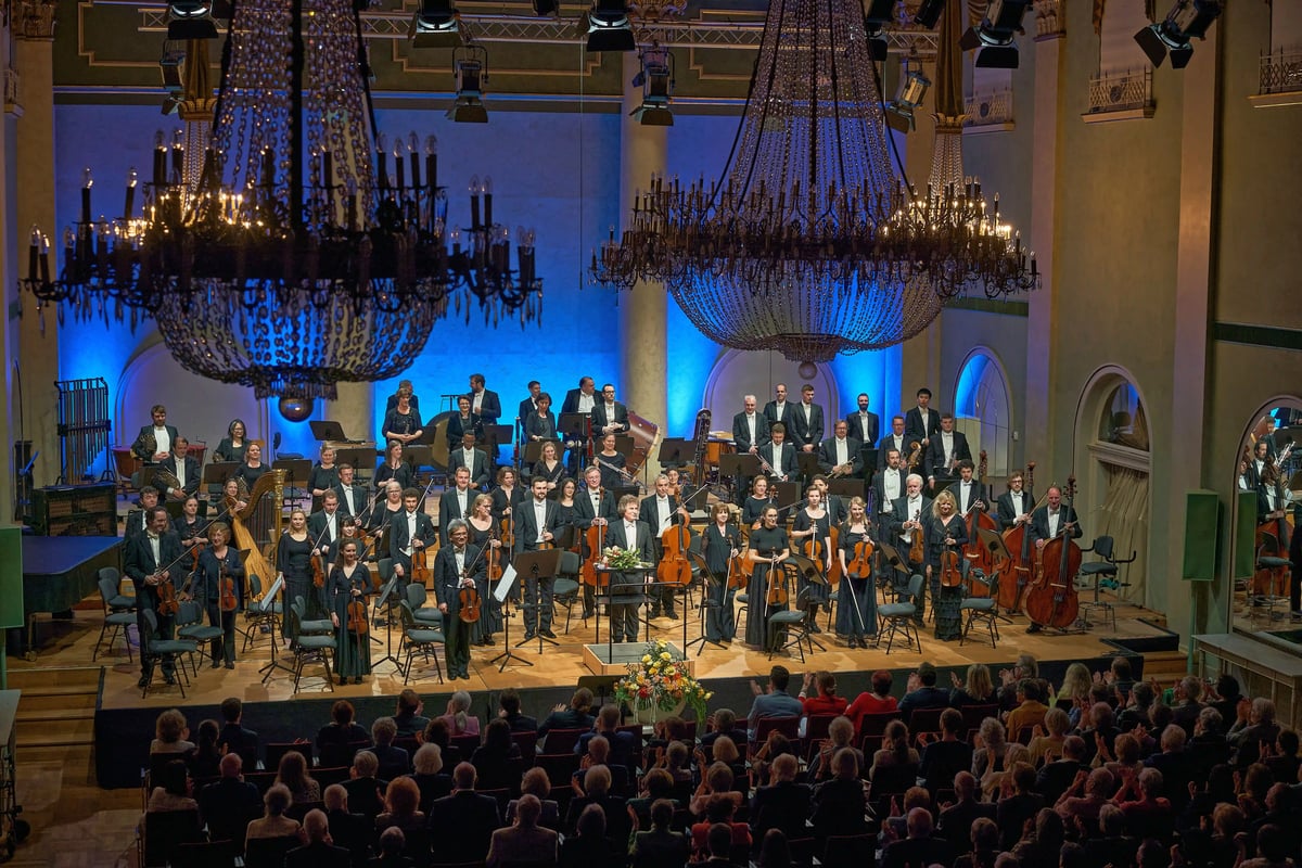 Die Philharmonie Baden-Baden auf der Bühne eines festlich beleuchteten Konzertsaals.