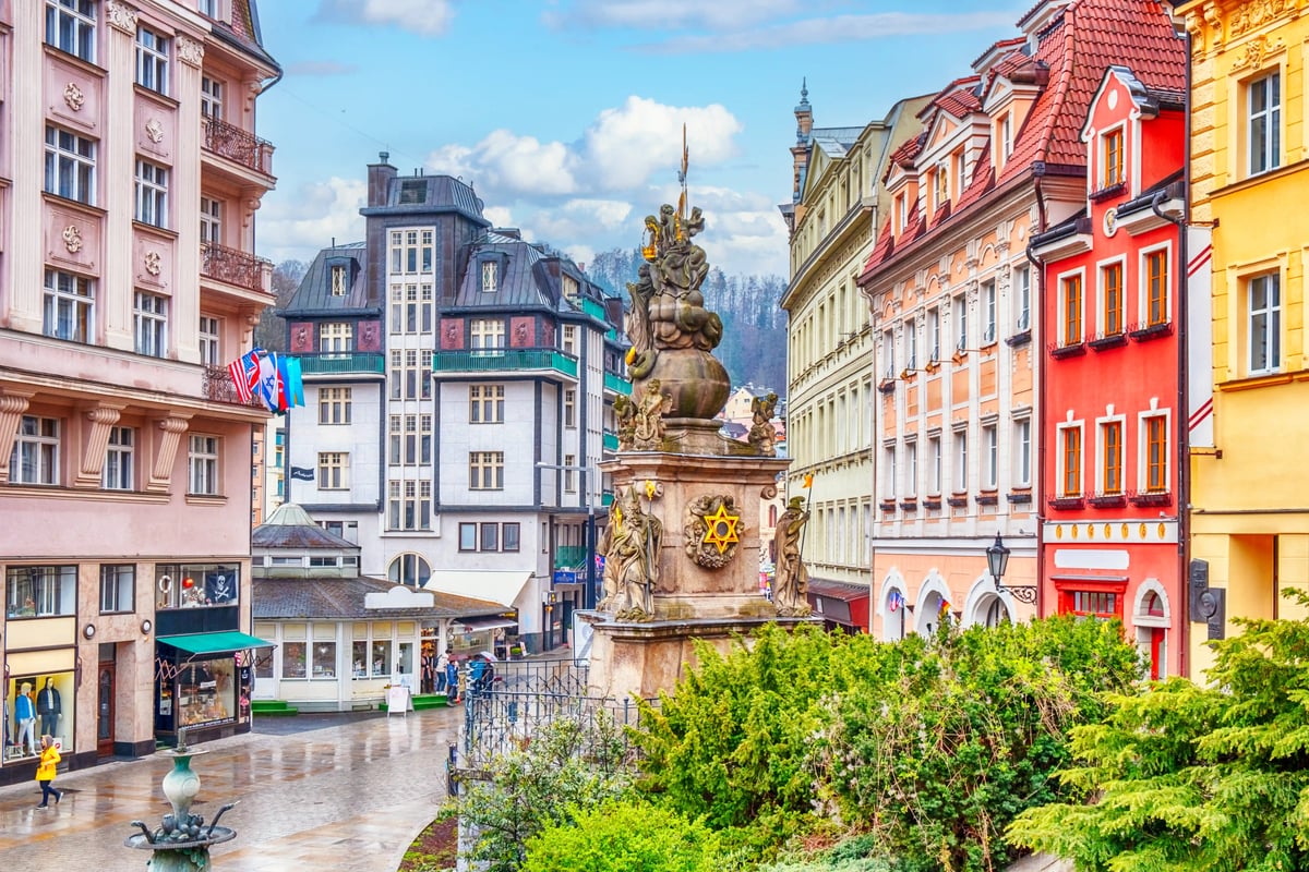 Blick auf die Altstadt von Karlsbad mit barocker Säule, bunten Häusern und nassem Kopfsteinpflaster