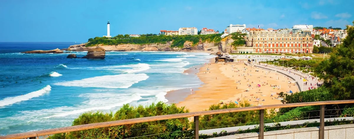 Sandstrand und Küste von Biarritz mit Leuchtturm, Wellen und eleganten Hotels.