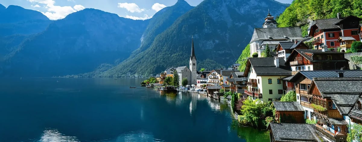 Hallstatt mit Kirche und historischen Häusern am Hallstätter See vor imposanter Bergkulisse.
