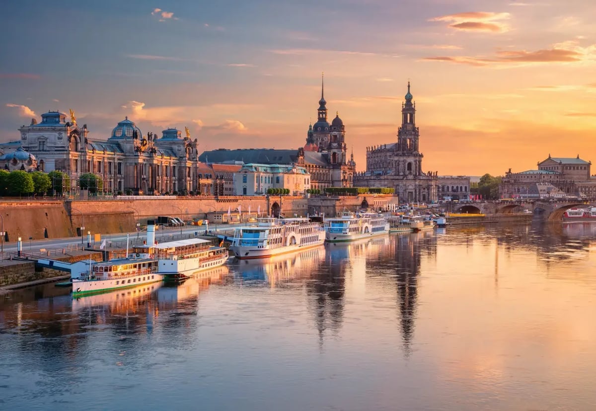 Elbufer in Dresden mit historischen Bauwerken, Flusskreuzfahrtschiffen und Abendstimmung.