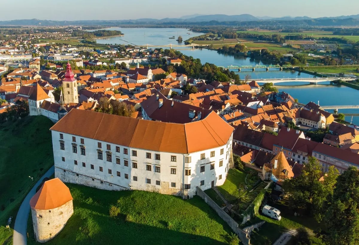 Luftaufnahme der Altstadt von Ptuj mit Schloss und der Drau im Hintergrund.