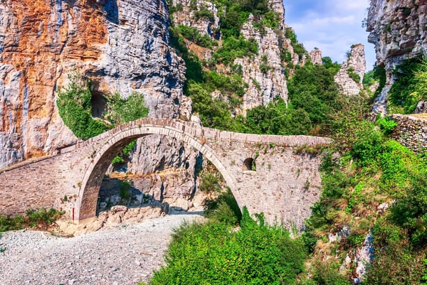 Steinerne Noutsos Brücke spannt sich über ein trockenes Flussbett zwischen steilen Felsen im Zagori Gebiet
