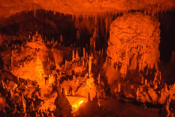 Beleuchtete Tropfsteinhöhle von Perama mit Stalaktiten und Stalagmiten in warmen Orangetönen