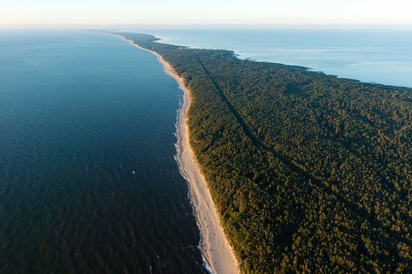Luftaufnahme der Kurischen Nehrung mit langem Sandstrand, dichtem Wald und der Ostsee entlang der Küste