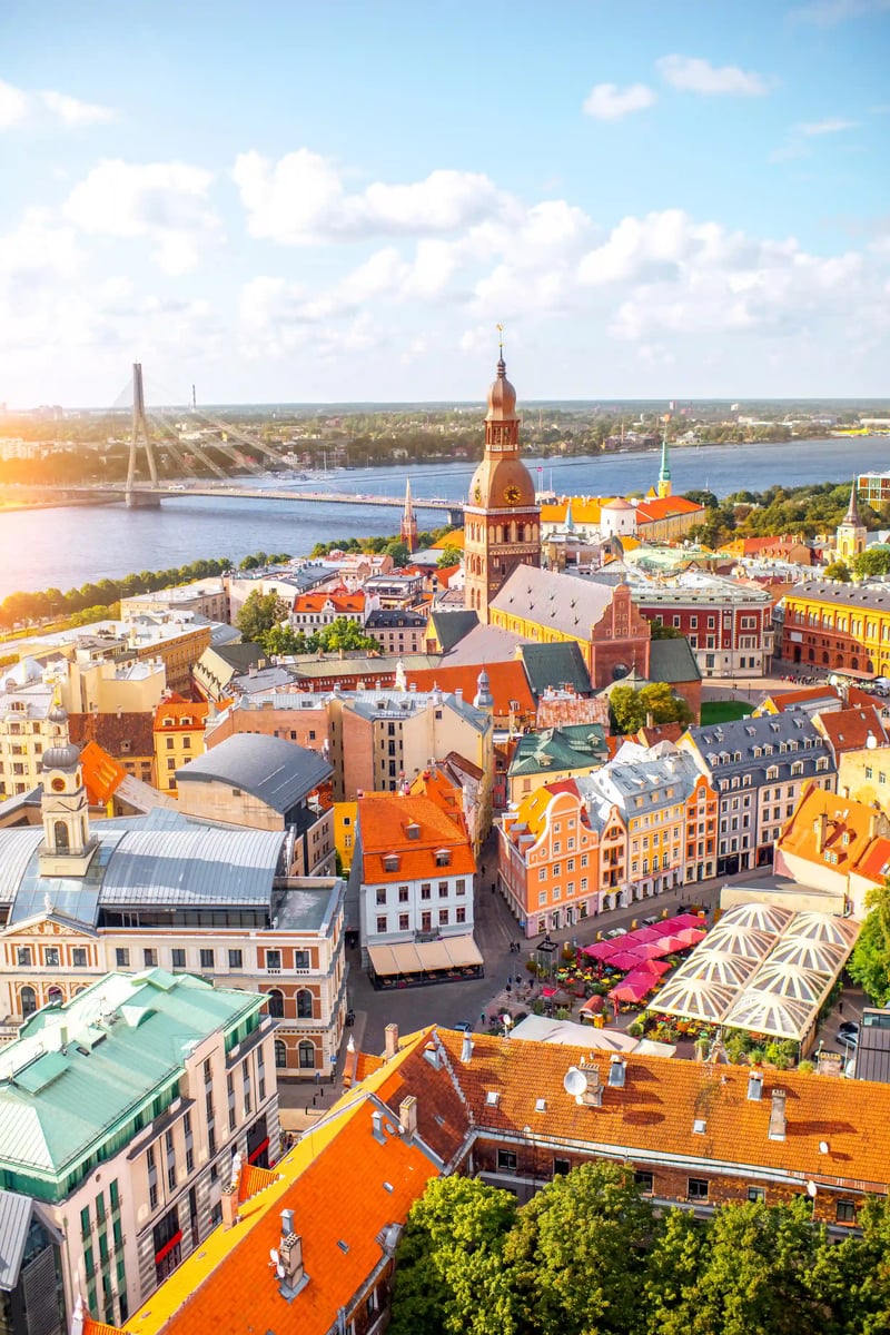Blick über die Altstadt von Riga mit roten Dächer, Kirchturm, Markthallen und Fluss im Hintergrund
