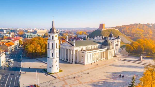 Luftaufnahme der Kathedrale von Vilnius mit Glockenturm, grossem Platz und herbstlich gefärbten Bäumen