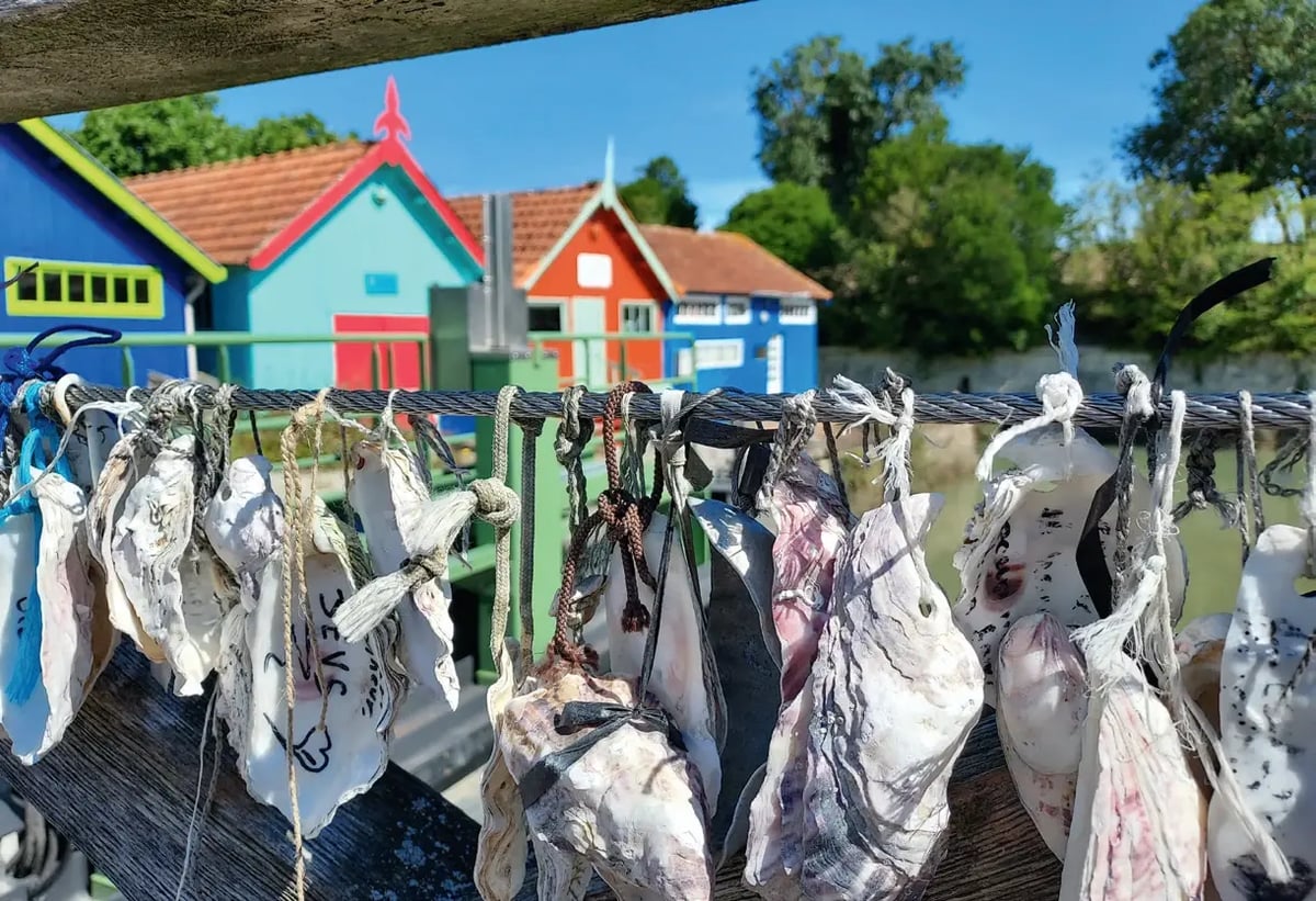 Frische Austern hängen zum Trocknen vor bunten Austernhütten auf der Île d’Oléron.
