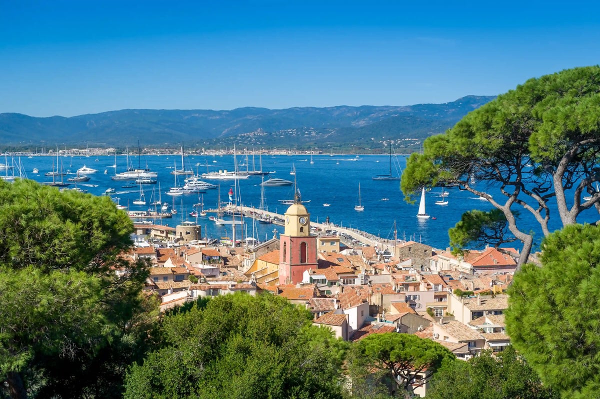 Blick auf den Hafen von Saint Tropez mit Kirche, Segelbooten und Bergen im Hintergrund