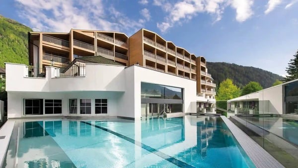 Modernes Hotel mit Aussenpool, klaren Linien, Glasfassaden und Berglandschaft im Hintergrund