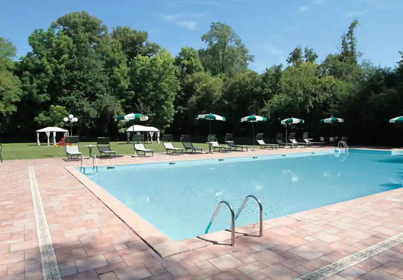 Aussenpool der Villa Luppis mit Liegestühlen, Sonnenschirmen und grossem Garten