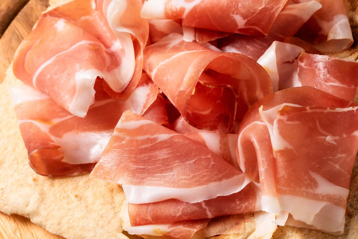 Dünn geschnittener San-Daniele-Schinken auf frischem Brot angerichtet