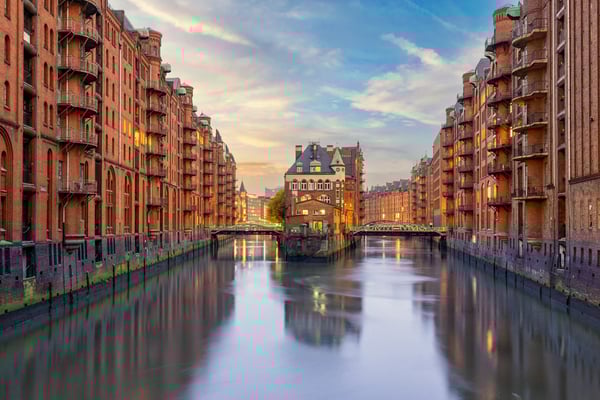 Speicherstadt in Hamburg mit historischen Backsteingebäuden, Fleeten und beleuchteten Brücken in der Abenddämmerung