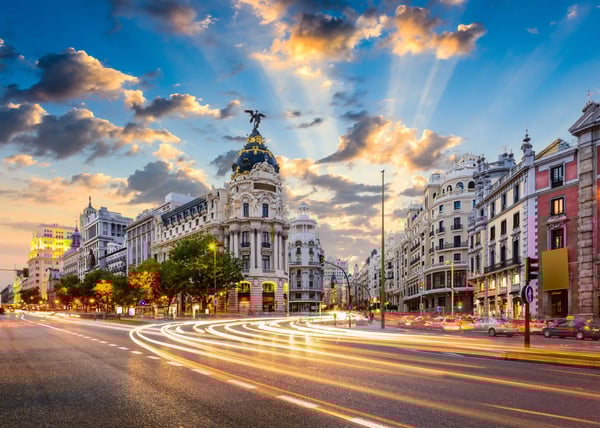 Gran Via in Madrid bei Abenddämmerung mit historischen Gebäuden und Lichtspuren des Verkehrs