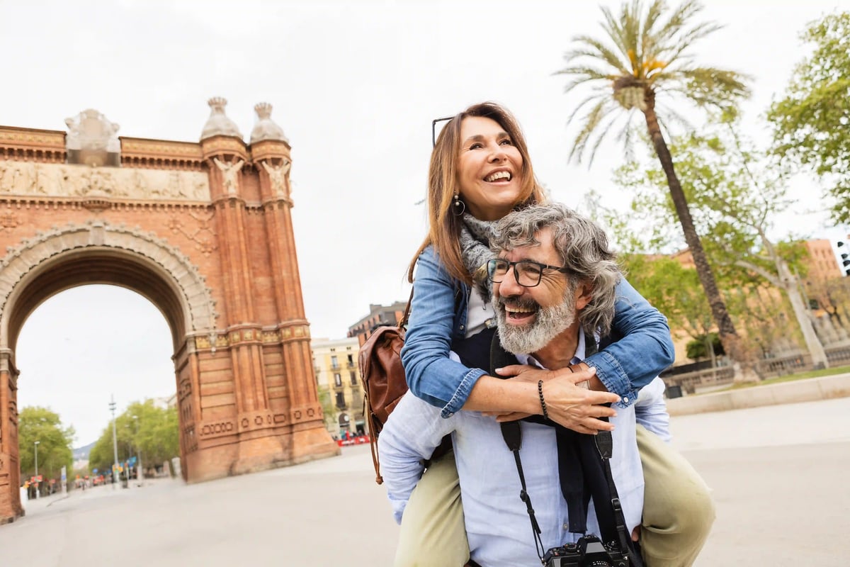 Paar lacht und umarmt sich vor dem Arc de Triomphe in Barcelona