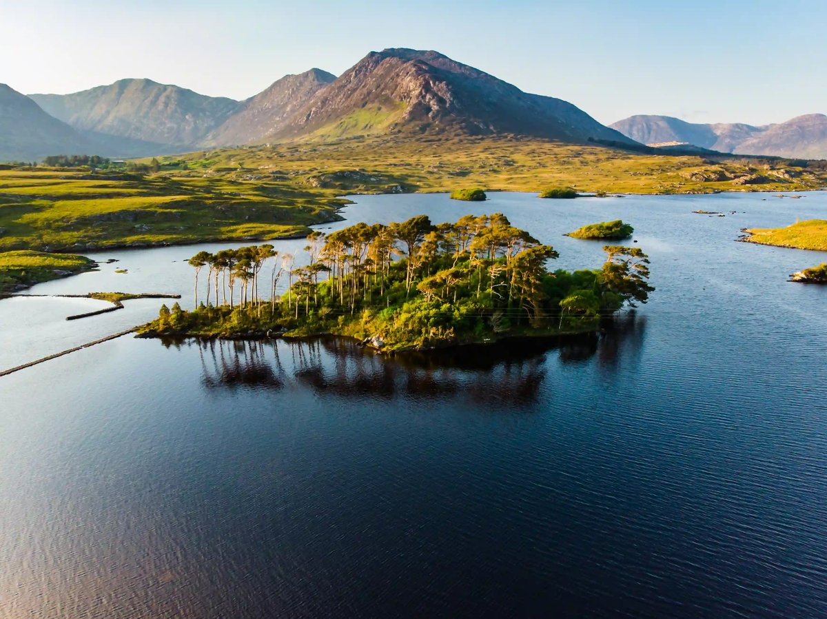 Berglandschaft im Connemara Nationalpark mit See, Felsen, grüner Vegetation und dramatischem Wolkenhimmel