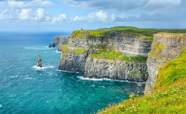 Hohe Steilküste der Cliffs of Moher mit markanten Felsformationen, Atlantik und grünem Gras im Vordergrund