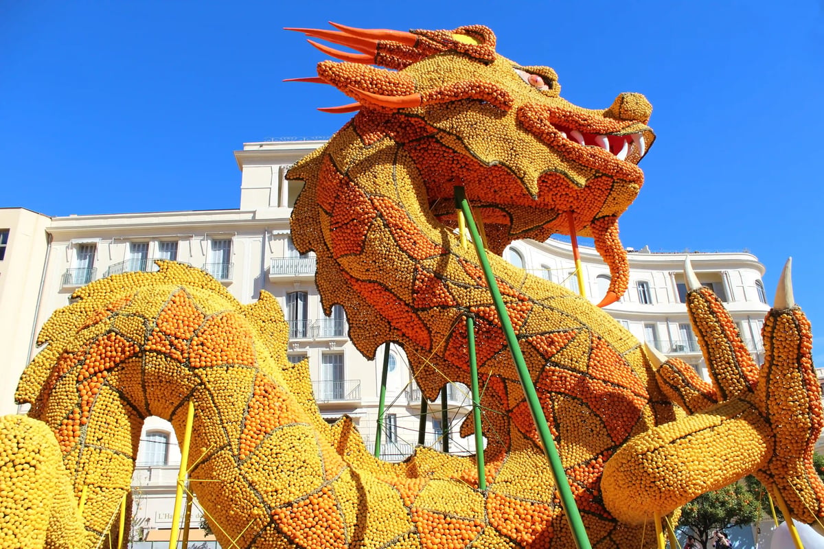 Grosse Drachenfigur aus Zitronen während des Zitronenfestes in Menton vor blauem Himmel