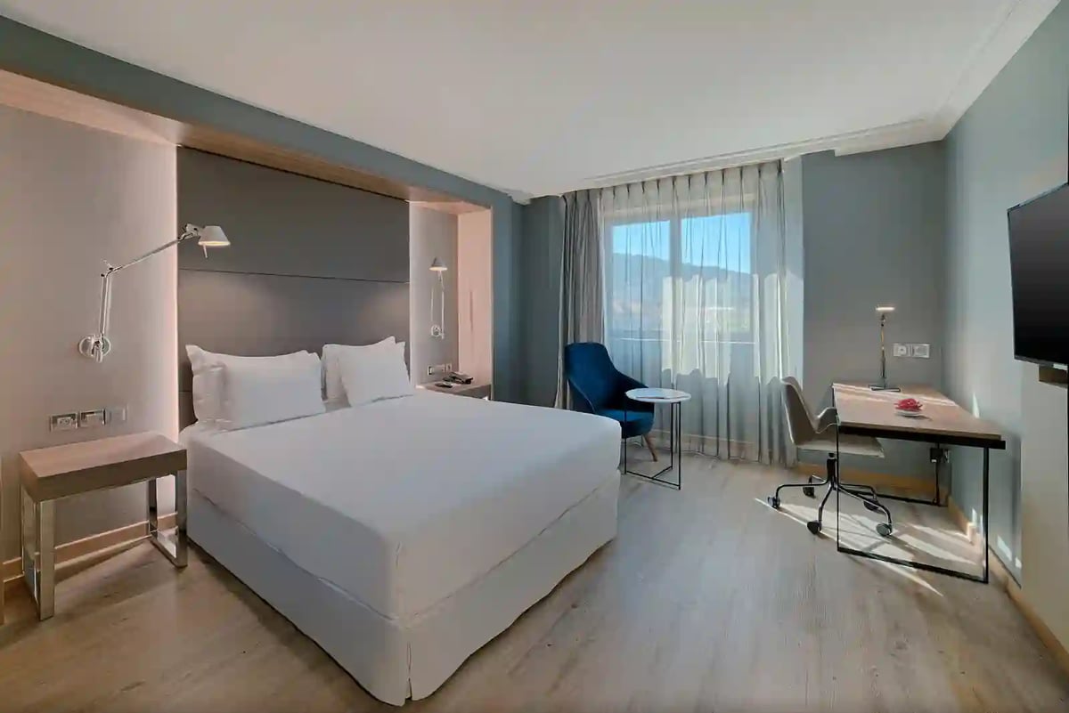 Modernes Hotelzimmer in Nizza mit Doppelbett, Schreibtisch, Sessel und Fenster mit Tageslicht
