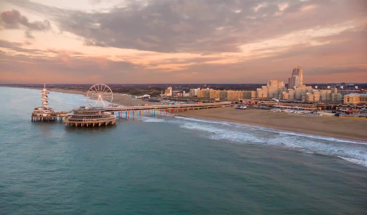 Luftaufnahme von Scheveningen mit Pier, Riesenrad und langem Sandstrand.
