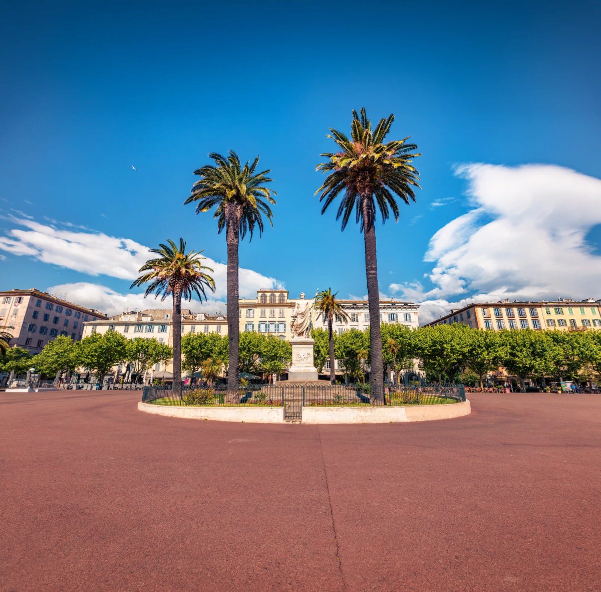 Place Foch in Ajaccio mit Napoleon-Statue, Palmen und historischen Fassaden unter blauem Himmel
