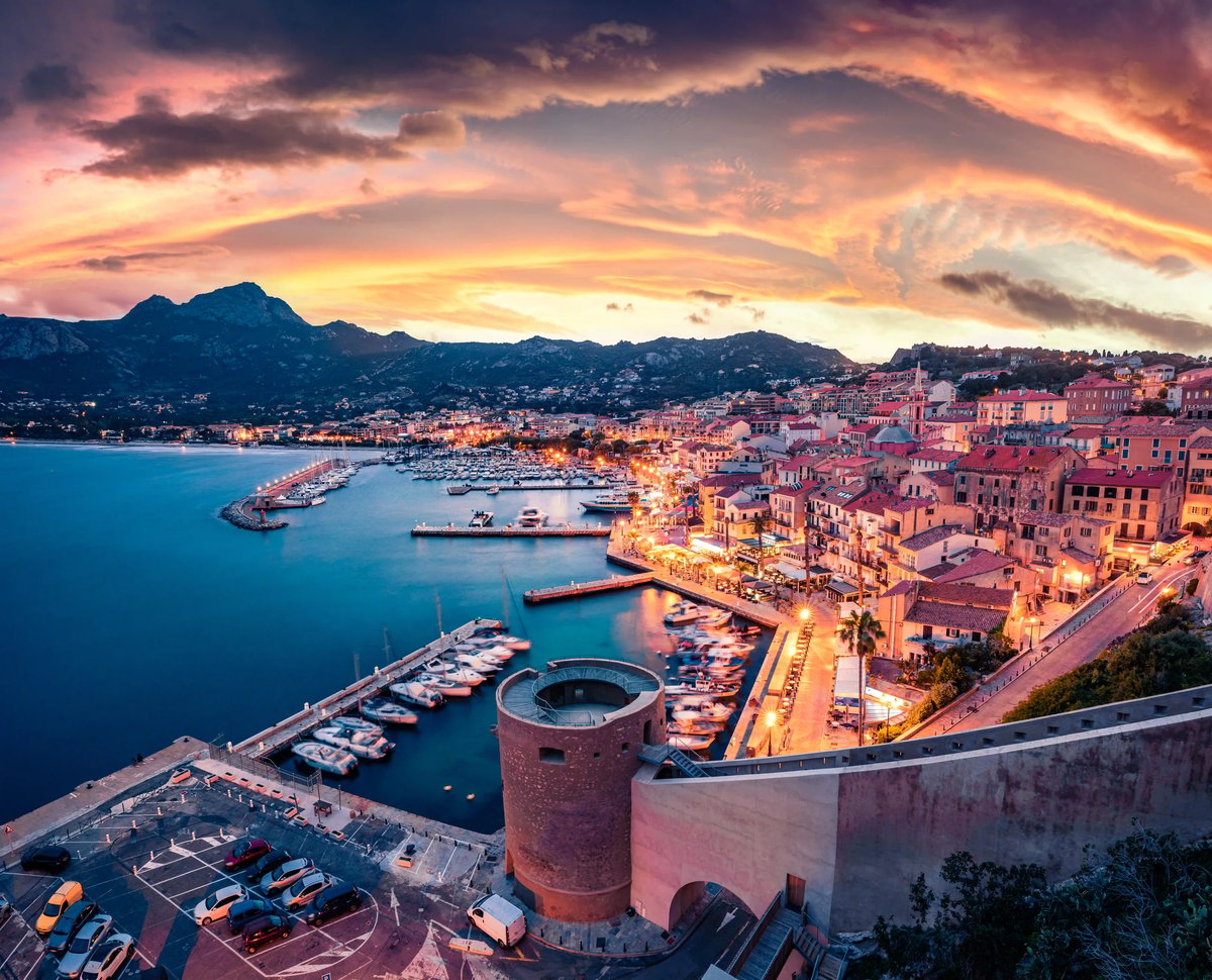 Hafen von Calvi mit Altstadt, Yachthafen und Bergen bei Sonnenuntergang