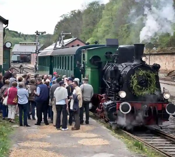 Historische Dampflok Train 1900 mit Fahrgästen am Bahnhof