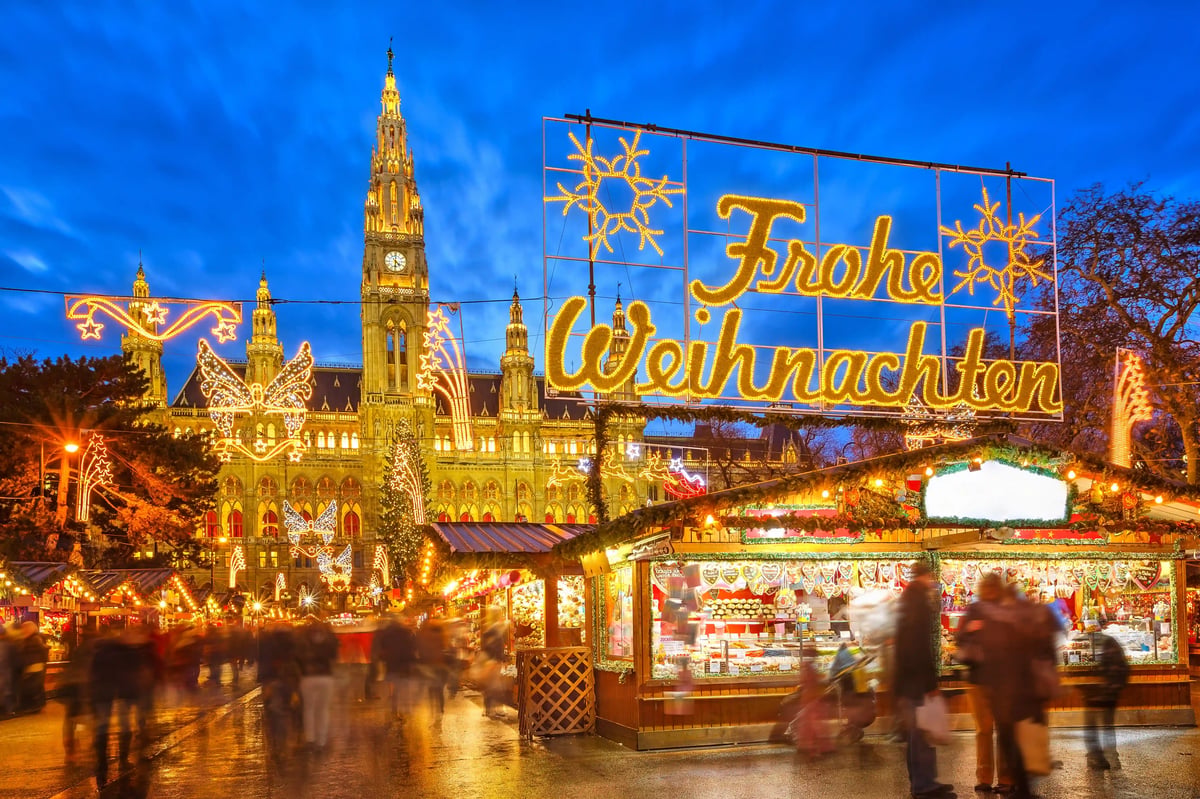 Weihnachtsmarkt vor dem Wiener Rathaus mit beleuchtetem Schriftzug Frohe Weihnachten
