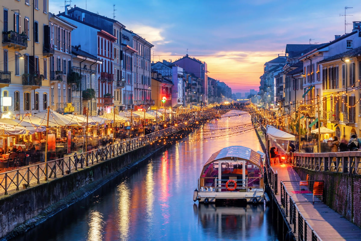 Abendstimmung am Navigli-Kanal mit Restaurants, Lichtern und Ausflugsboot in Mailand.