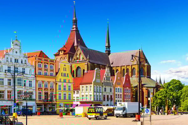 Historische Häuserfassaden und Kirche am Marktplatz von Rostock mit bunten Gebäuden und blauem Himmel