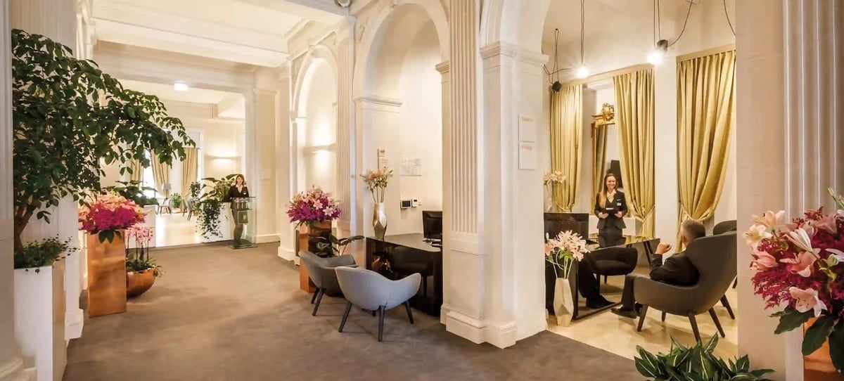Elegante Hotellobby mit hohen Boegen, Sitzgruppen, Blumenarrangements und gästefreundlicher Atmosphäre