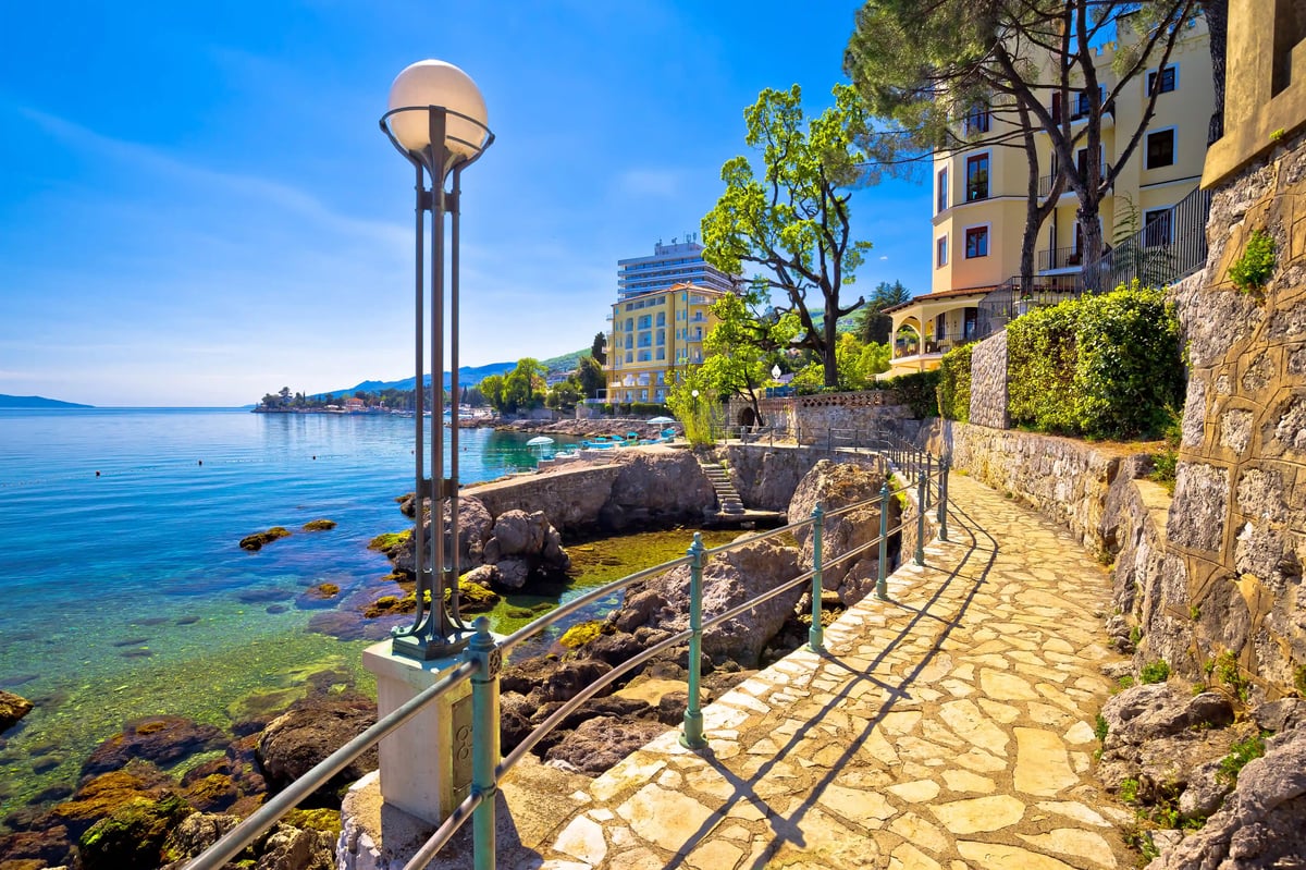 Steinerner Uferweg in Opatija mit Geländer, Laterne und Blick auf ruhiges Meer und Hotels