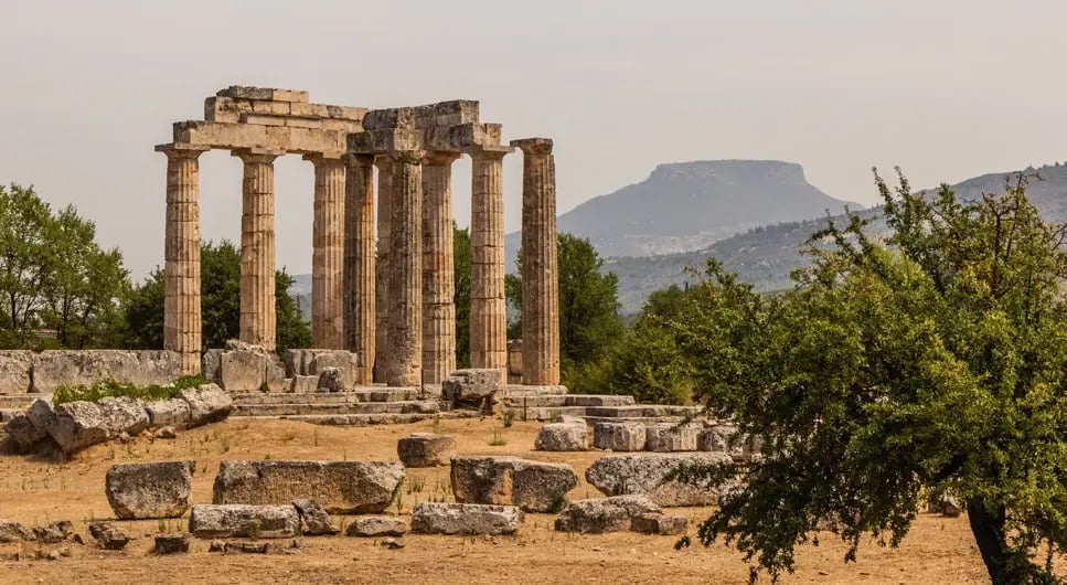 Ruinen des Zeus-Tempels in Olympia vor hügeliger Landschaft.