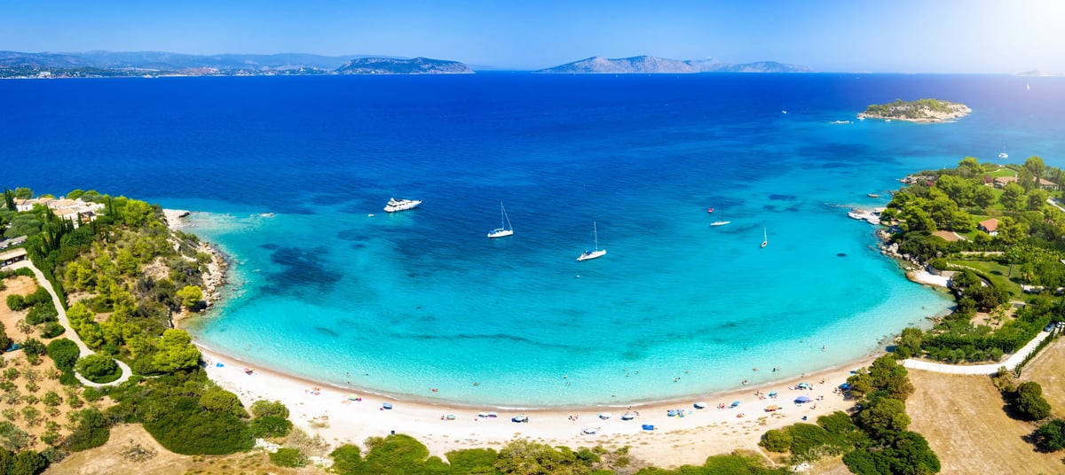 Türkisfarbene Badebucht an der Küste des Peloponnes mit Segelbooten.