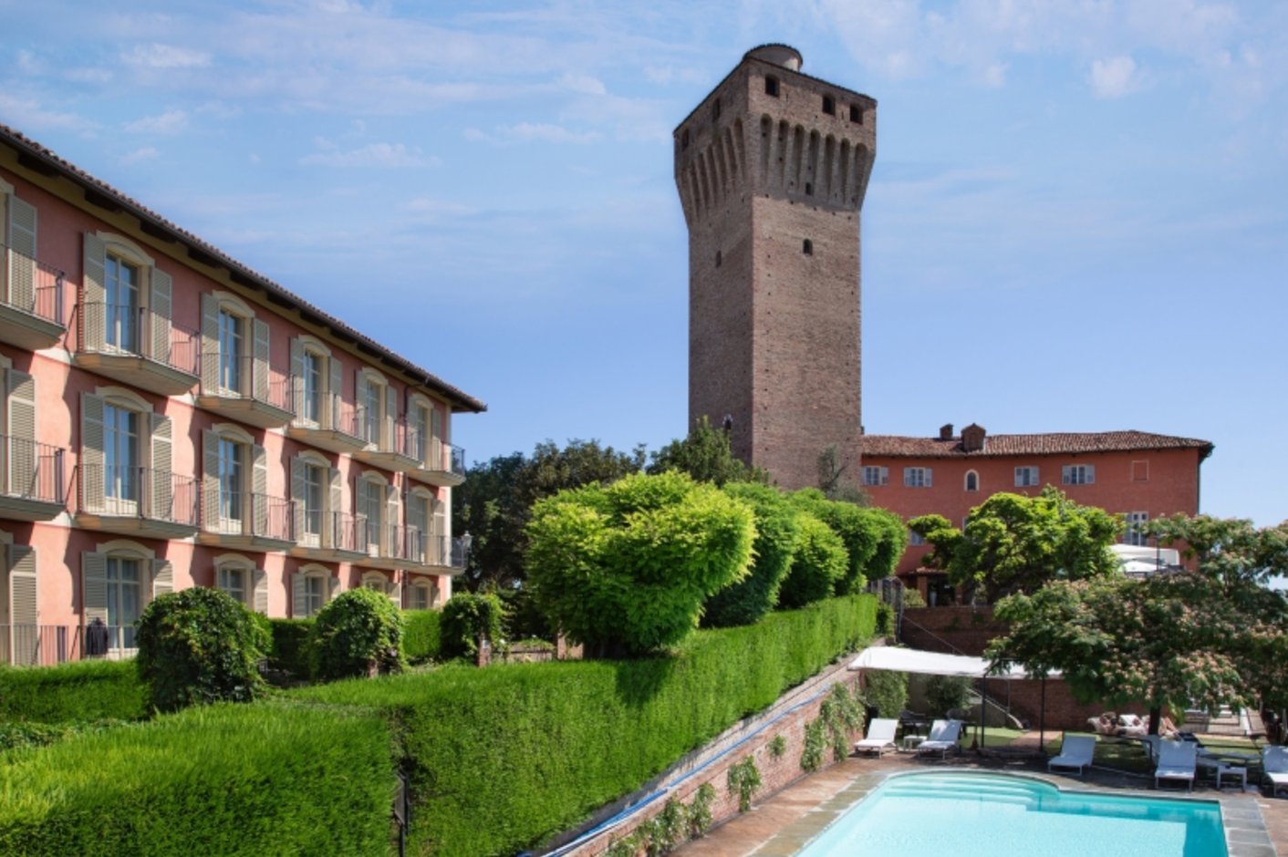 Historisches Hotelensemble mit mittelalterlichem Turm, gepflegten Hecken und Aussenpool in ruhiger Lage mit Blick auf die italienische Landschaft.