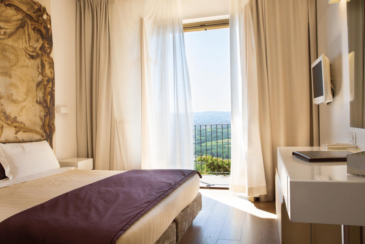 Stilvoll eingerichtetes Hotelzimmer mit Doppelbett, Balkon und Blick auf die Landschaft