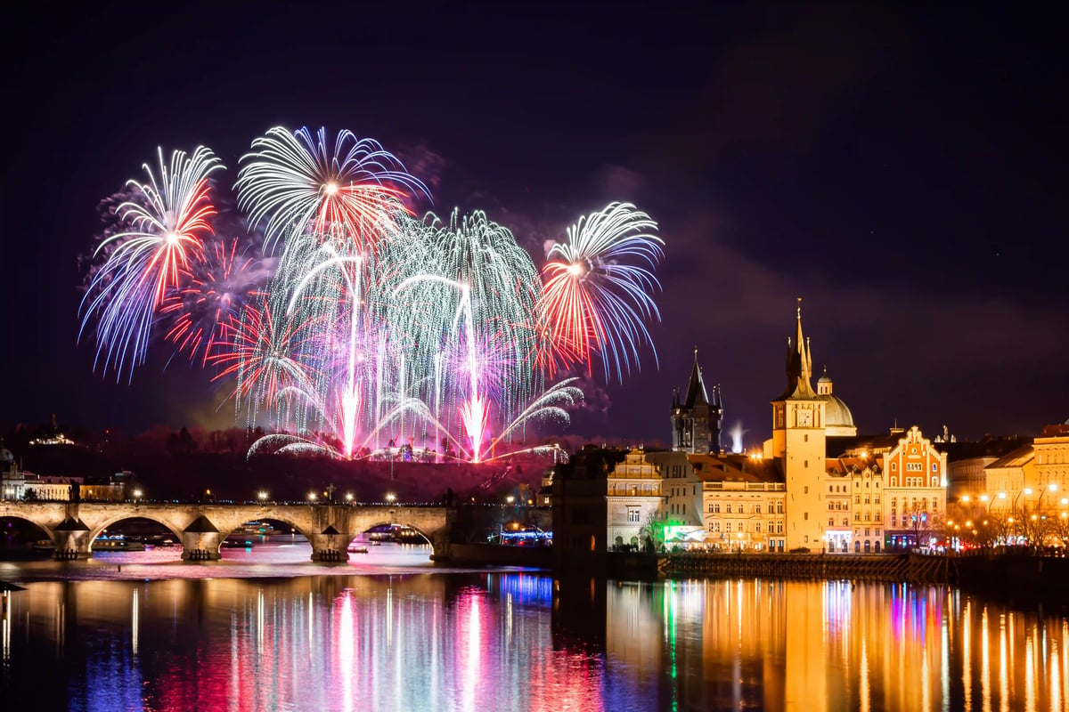 Feuerwerk über der Prager Altstadt mit Karlsbrücke und Spiegelungen in der Moldau an Silvester
